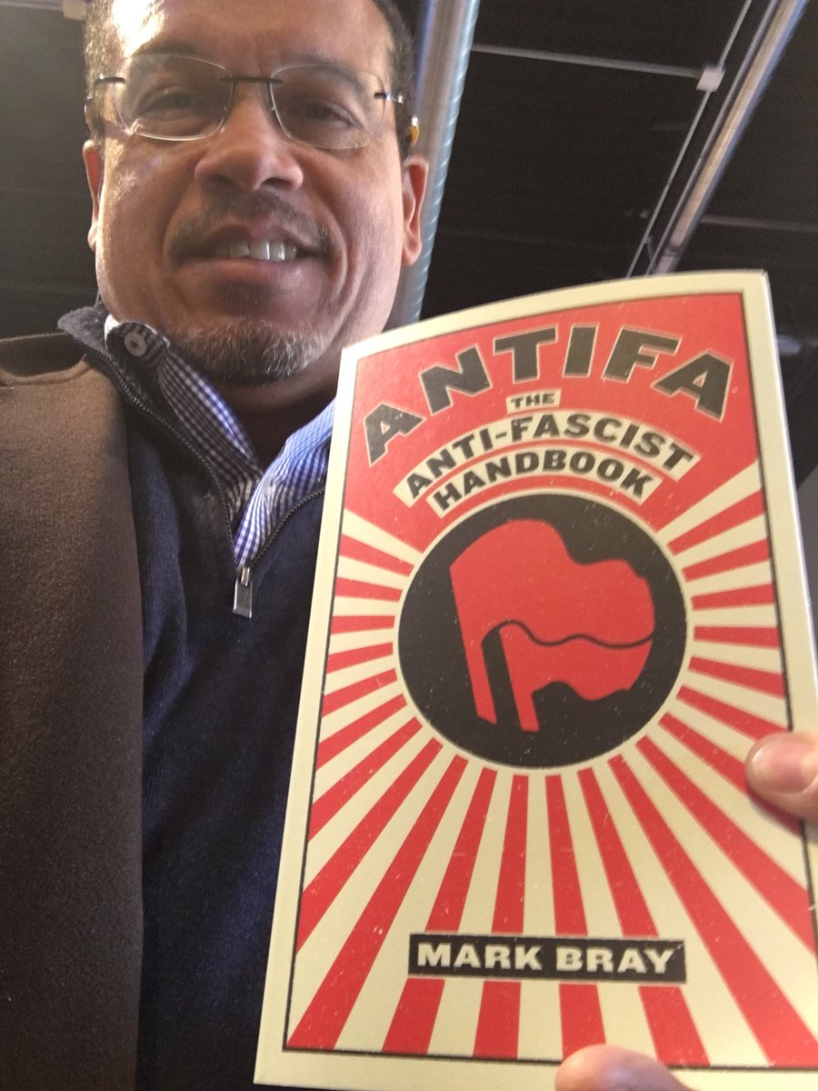 Keith Ellison - Democratic Party's number one henchman with a copy of the ANTIFA handbook by Mark Bray